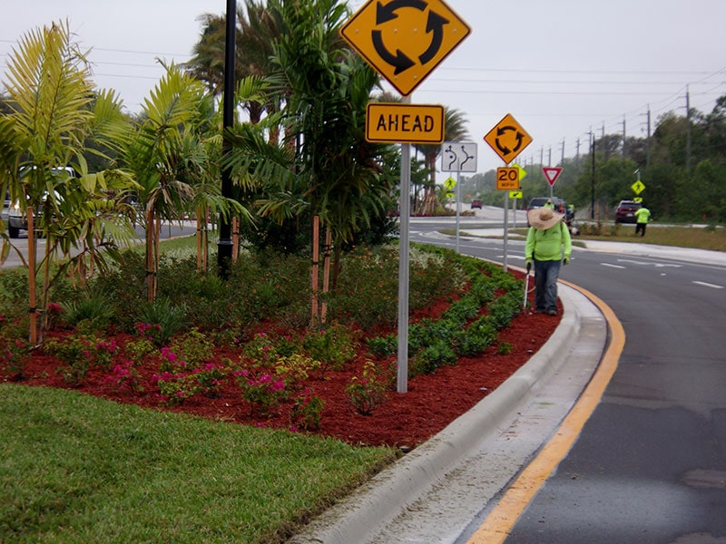 P & T Landscaping team weed eating and trimming shrubs on the Bonita Springs median