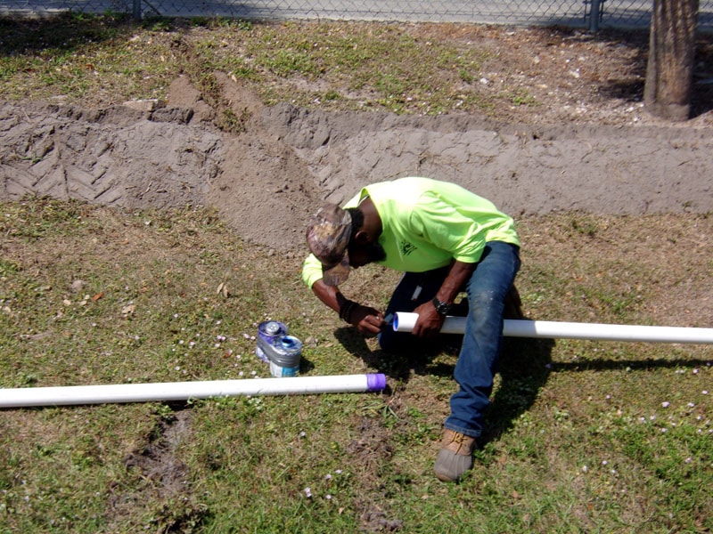 Irrigation and Lighting Team Adding Glue to Pipes on the Ground